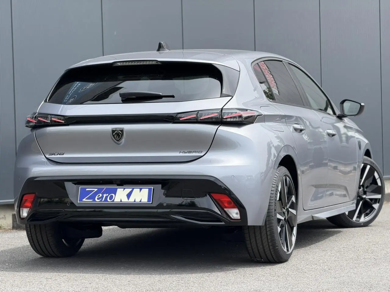 Vue 3/4 arrière droite d'une Peugeot 308 gris Artense avec feux arrière à LED en forme de griffes et jantes alliage bi-tons.