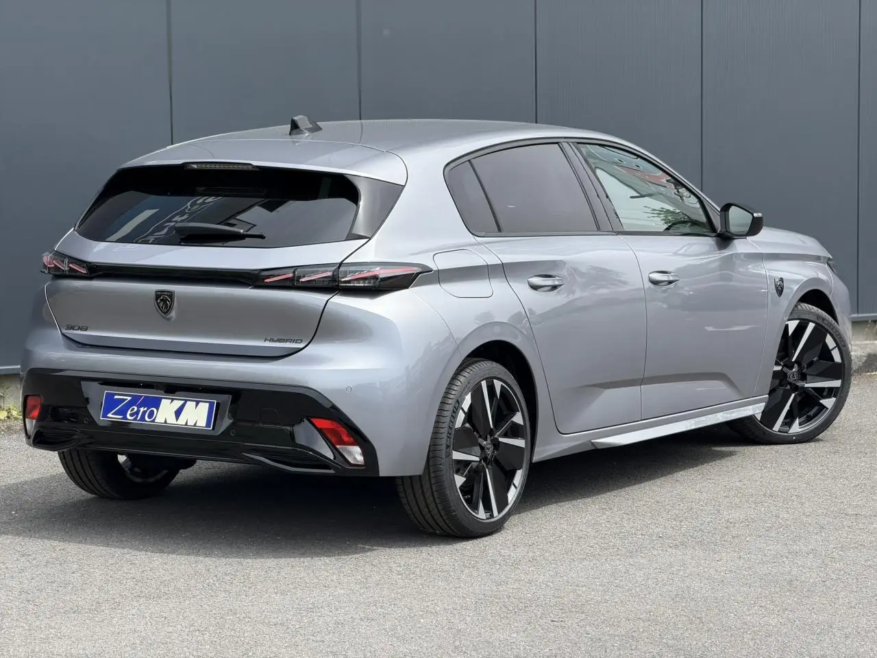 Peugeot 308 NV Hybrid gris Artense vue 3/4 arrière droit, jantes bi-tons et feux arrière LED 3 griffes.