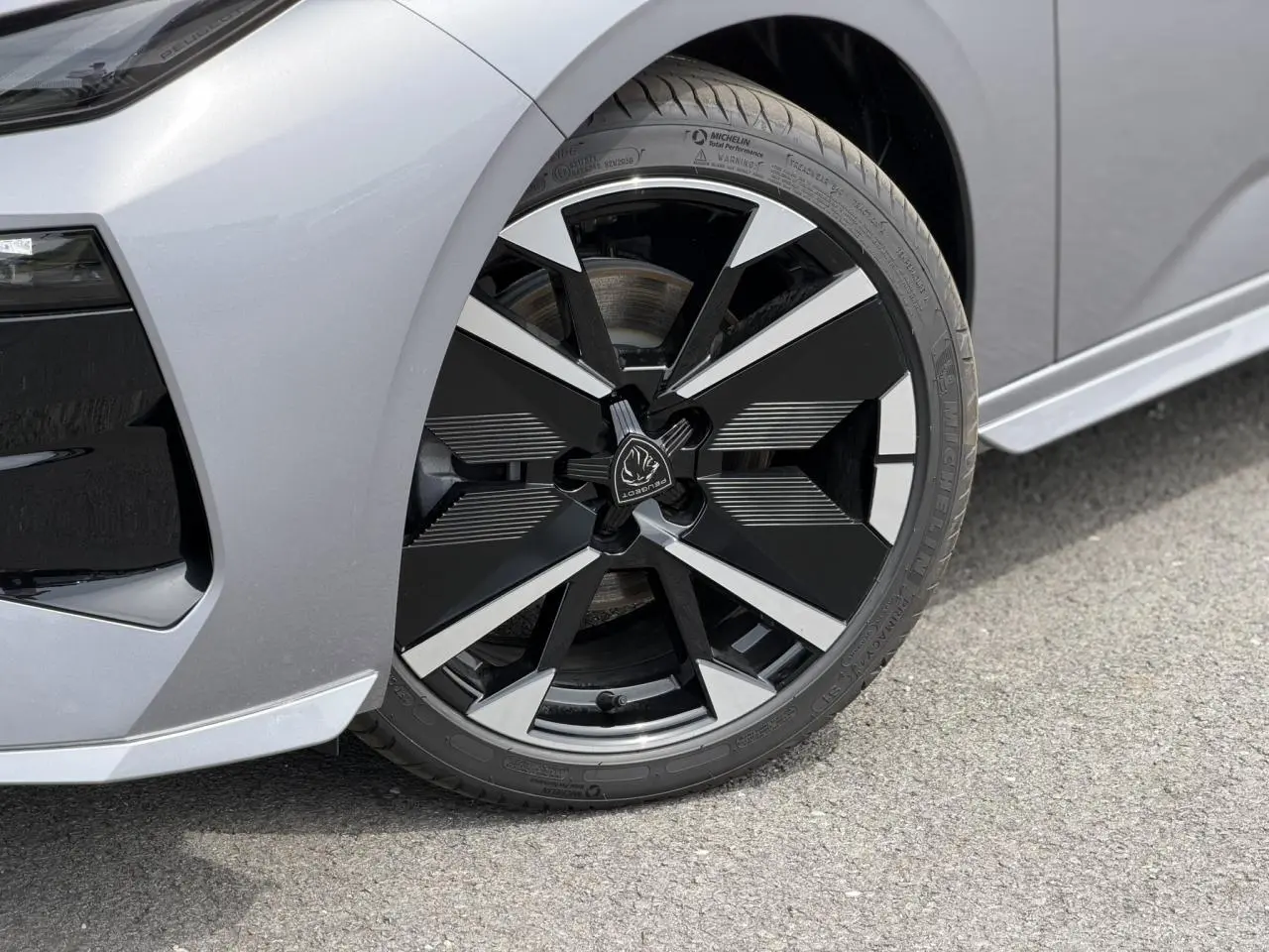 Gros plan sur la roue avant gauche de la Peugeot 308 gris Artense avec jante alliage bi-ton noir et argent.