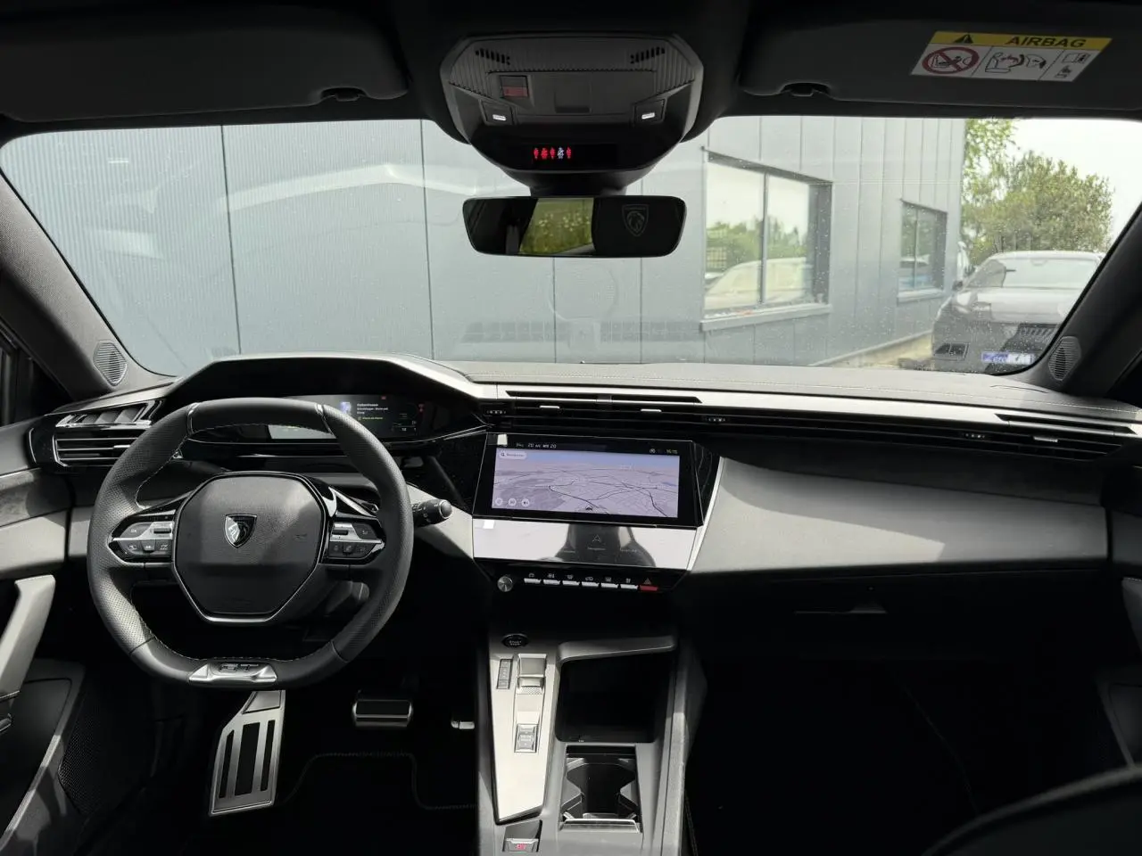 Vue avant de l'intérieur du Peugeot 308 gris Artense, avec volant compact GT et écran tactile central.