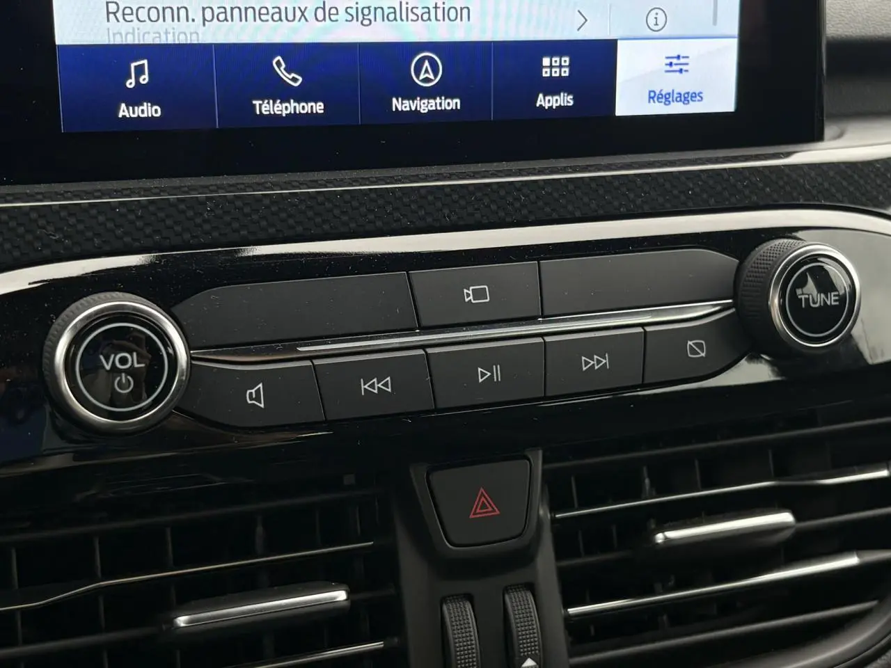 Détail de la console centrale du Ford Kuga 2023 avec commandes audio et écran tactile visible en partie.