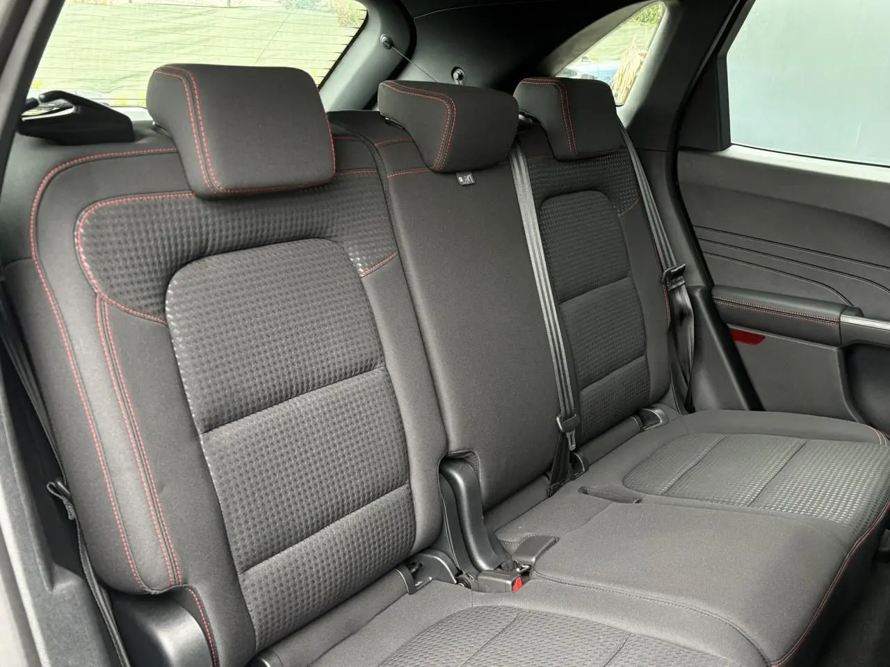 Vue latérale des sièges arrière noirs avec surpiqûres rouges du Ford Kuga 2.0 EcoBlue 120 BVA ST-Line 2023.