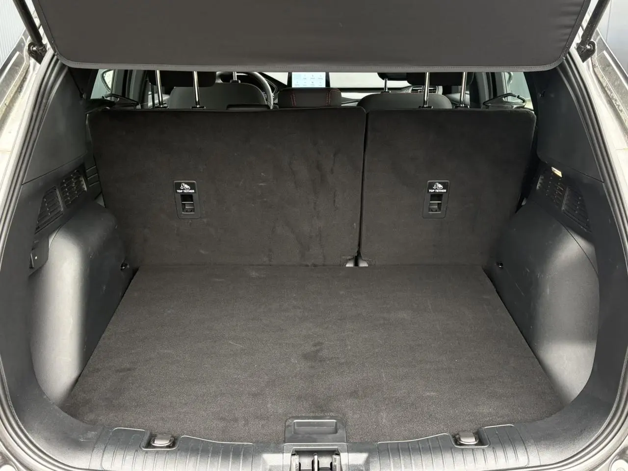 Coffre ouvert vu de l'arrière du Ford Kuga gris graphite, montrant l'espace de chargement et les dossiers arrière rabattus.