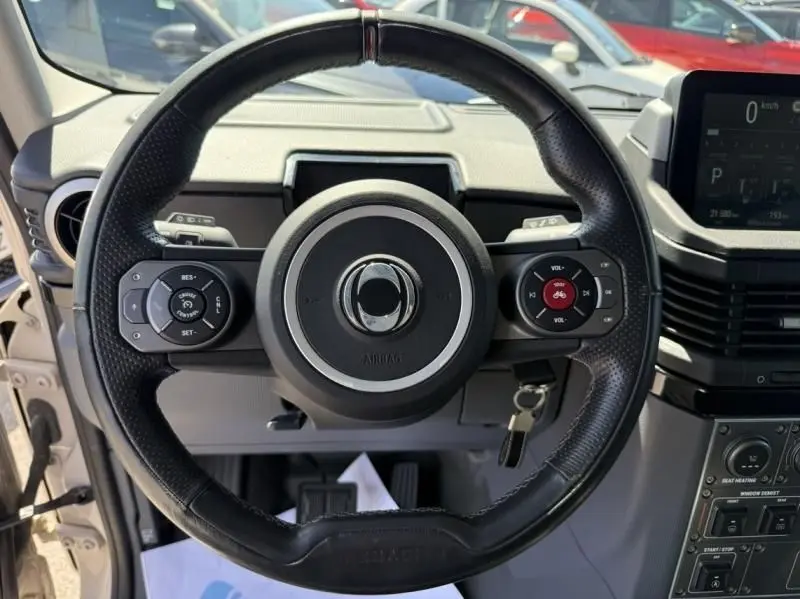 Vue centrée sur le volant noir du INEOS Grenadier beige 2024, montrant les commandes intégrées et le tableau de bord digital.