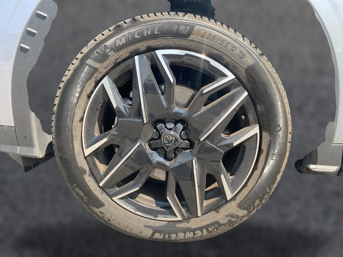 Gros plan sur la roue avant droite gris artense d’un Peugeot 5008 Hybrid 145 allure e-dcs6 avec jante alu noire et argent.