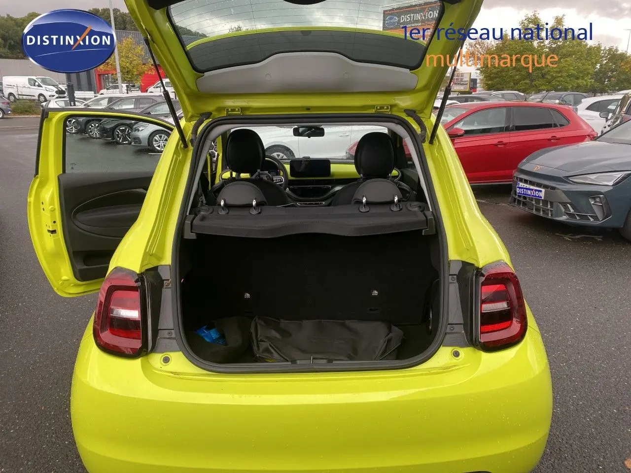 Vue arrière ouverte de la FIAT 500 électrique 2024 en jaune acid, coffre et porte côté gauche ouverts, intérieur visible.
