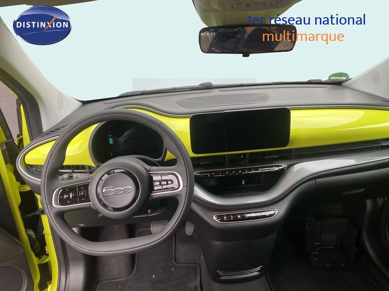 Vue intérieure avant du tableau de bord jaune acid de la Fiat 500 électrique 2024 avec volant multifonction et écran tactile.