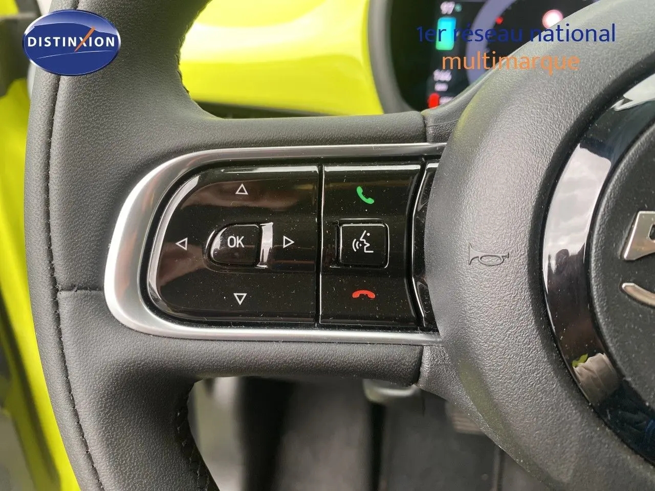 Gros plan sur les commandes gauche du volant d’une FIAT 500 électrique jaune acid 2024, avec boutons multifonctions.