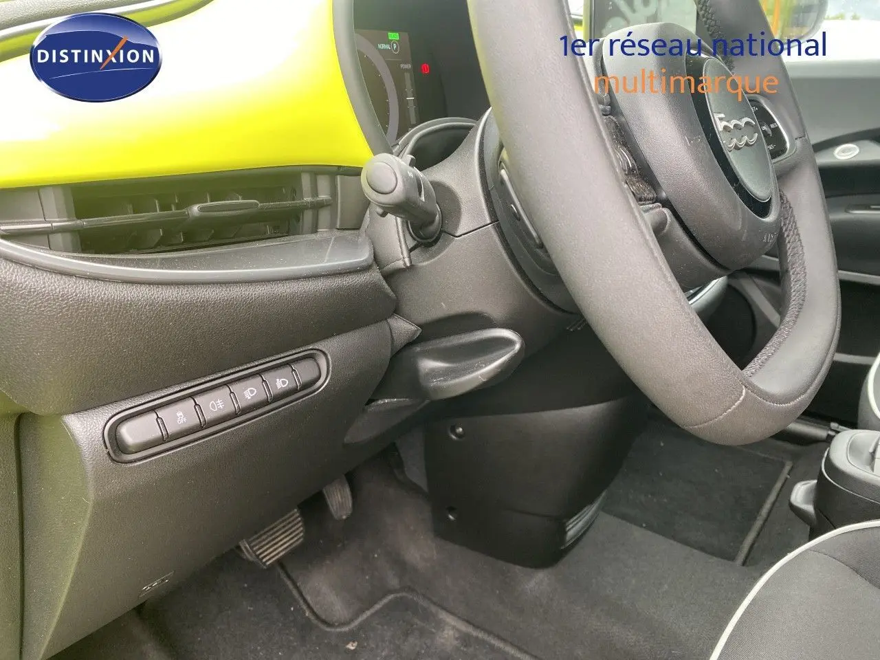 Vue intérieure côté conducteur de la FIAT 500 électrique 2024 avec tableau de bord jaune acid et volant cuir noir.