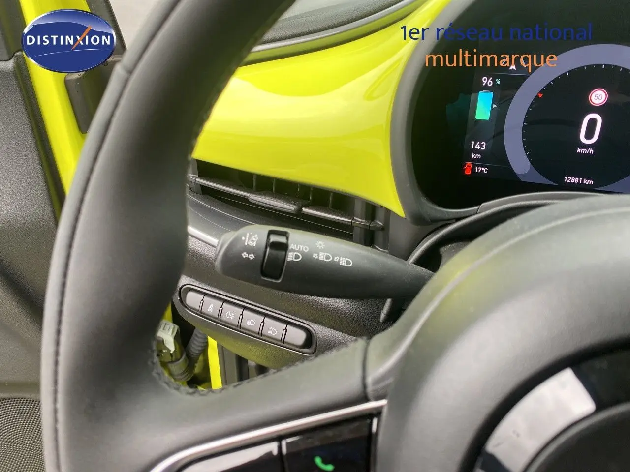 Vue intérieure centrée sur le volant et tableau de bord jaune acidulé de la FIAT 500 électrique 2024.