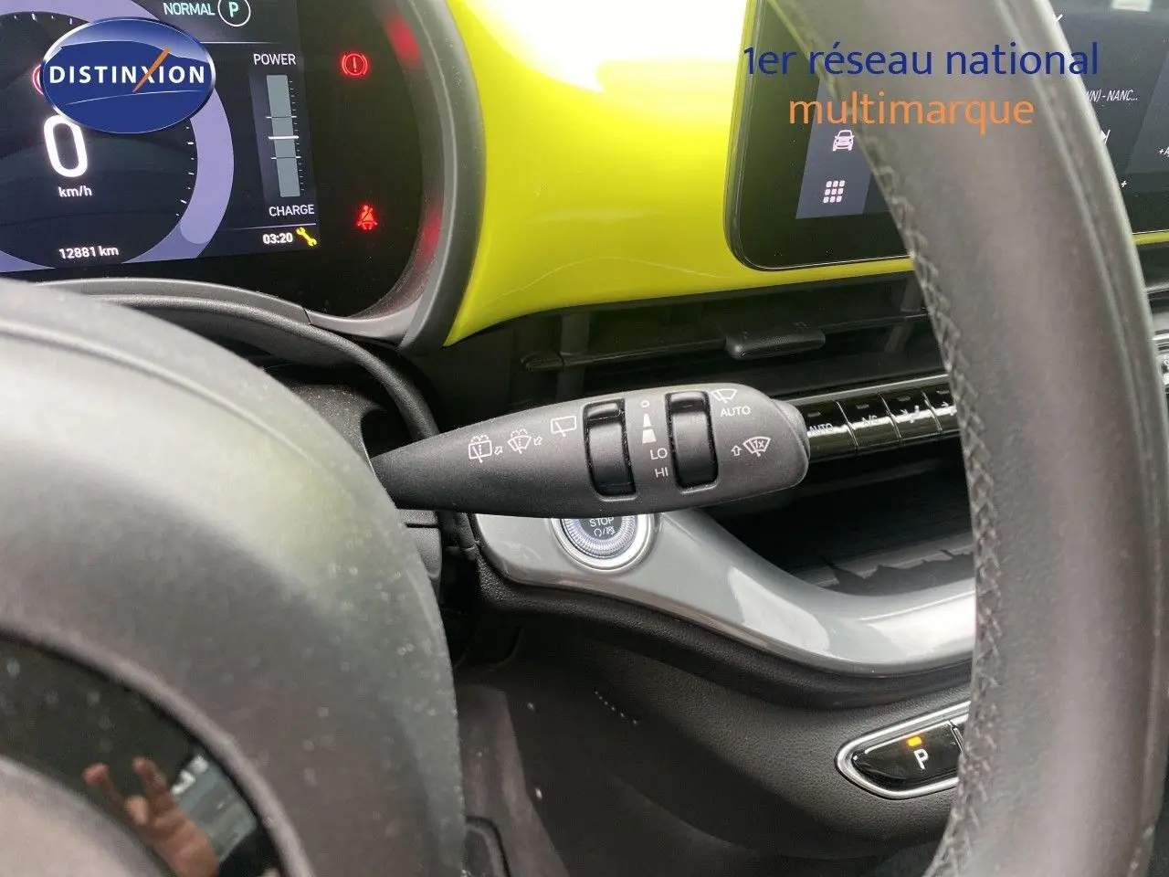 Vue intérieure rapprochée du volant et du tableau de bord jaune acidulé de la FIAT 500 électrique 2024.