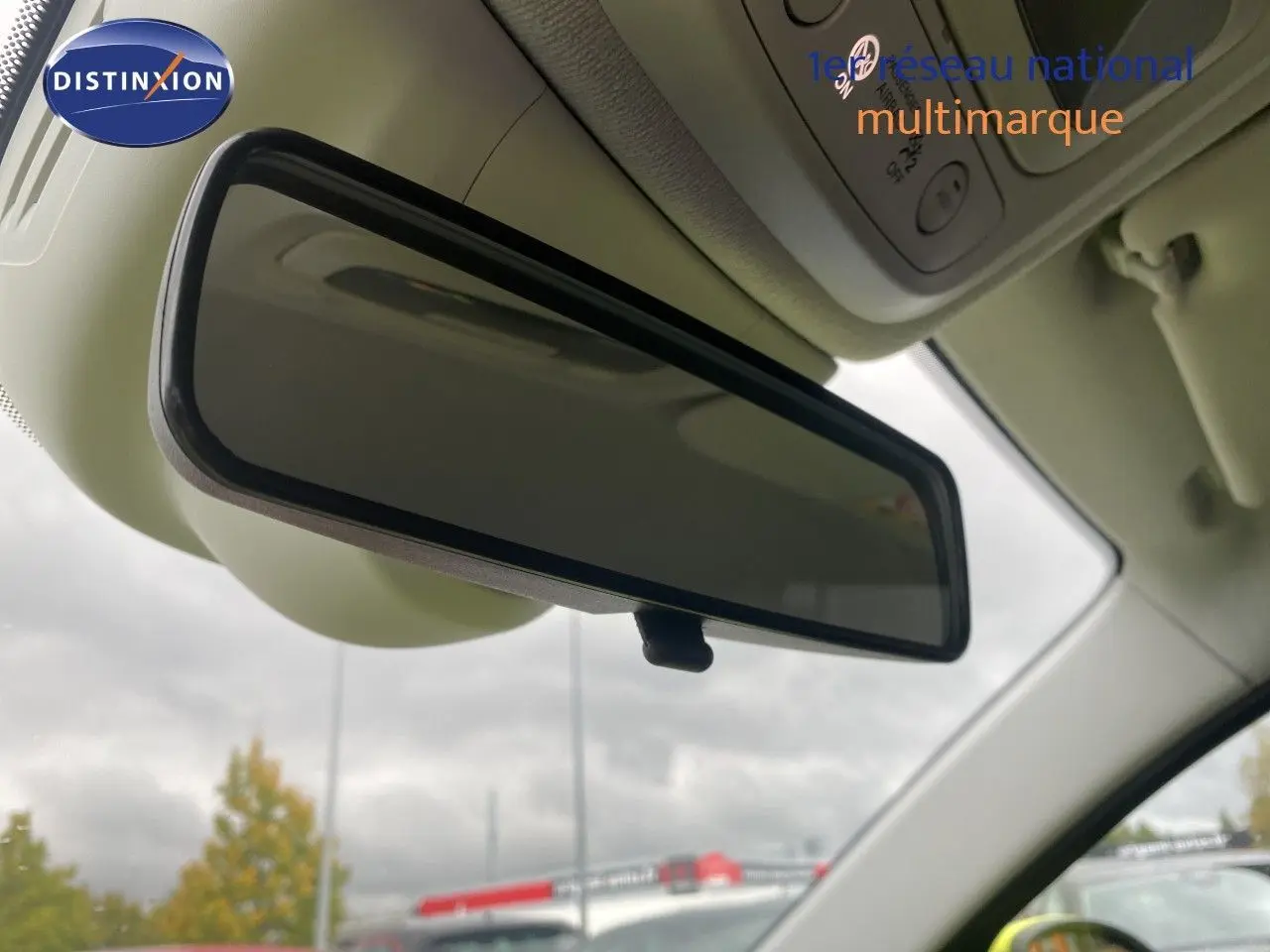 Rétroviseur intérieur de la FIAT 500 électrique 2024, vue rapprochée sous plafond clair avec ciel nuageux en arrière-plan.