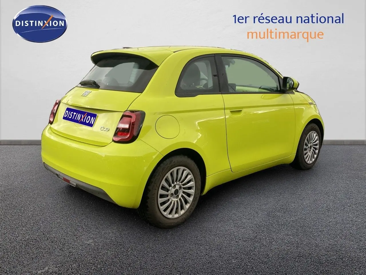 Fiat 500 électrique jaune acid vue 3/4 arrière côté droit sur fond neutre avec jantes originales.