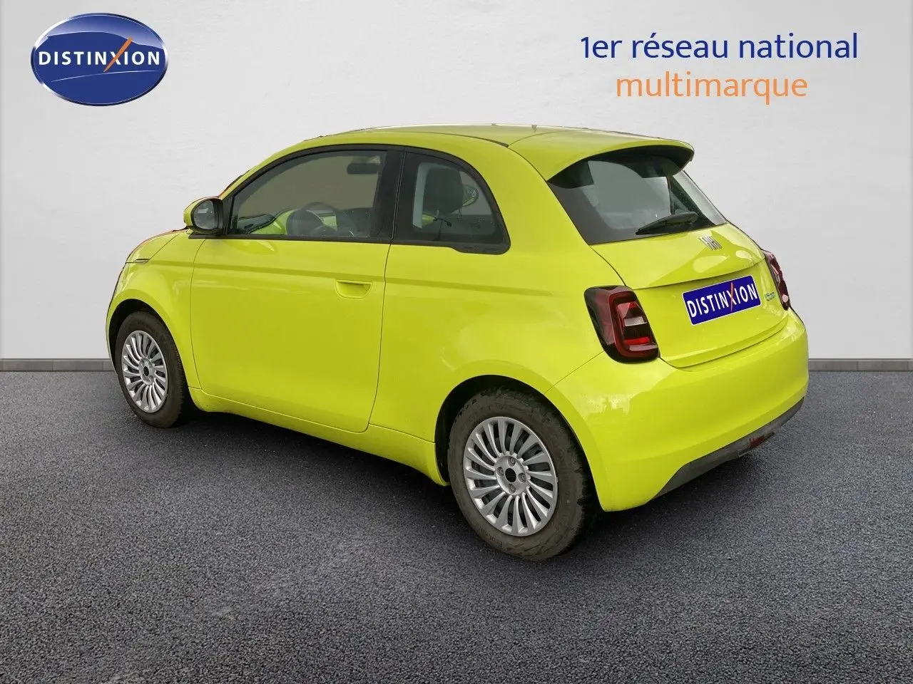 Vue 3/4 arrière droite d'une FIAT 500 électrique 2024 en jaune acid avec feux arrière foncés et jantes argentées.