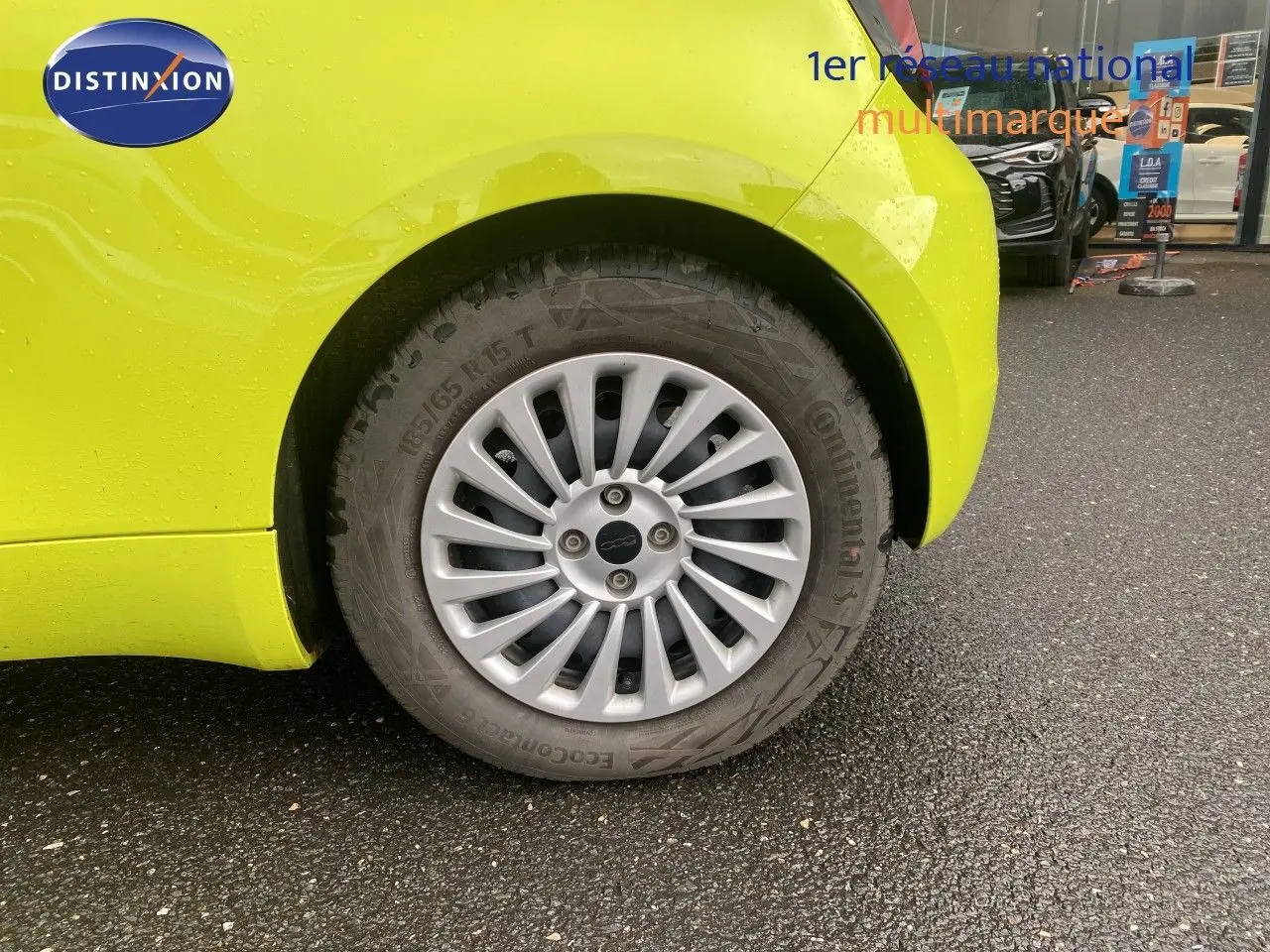 Gros plan sur la roue arrière droite d'une FIAT 500 électrique 2024 en jaune acid avec jante argentée multibranches.