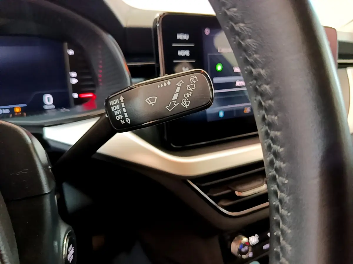 Gros plan sur la commande d'essuie-glace à gauche du volant cuir dans l'habitacle du Skoda Kamiq gris clair 2022.