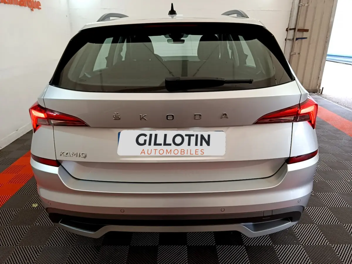 Vue arrière d'un Skoda Kamiq gris clair 2022 avec feux LED et logo ŠKODA bien visible sur un sol à damier noir et rouge.