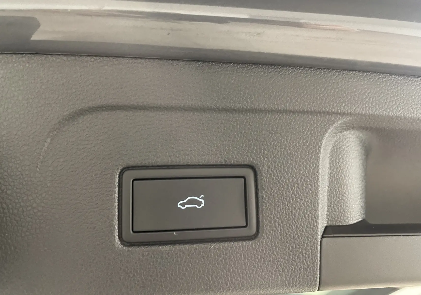 Bouton d'ouverture électrique du hayon sur le coffre du Volkswagen Touran Gris Dauphin 2024.
