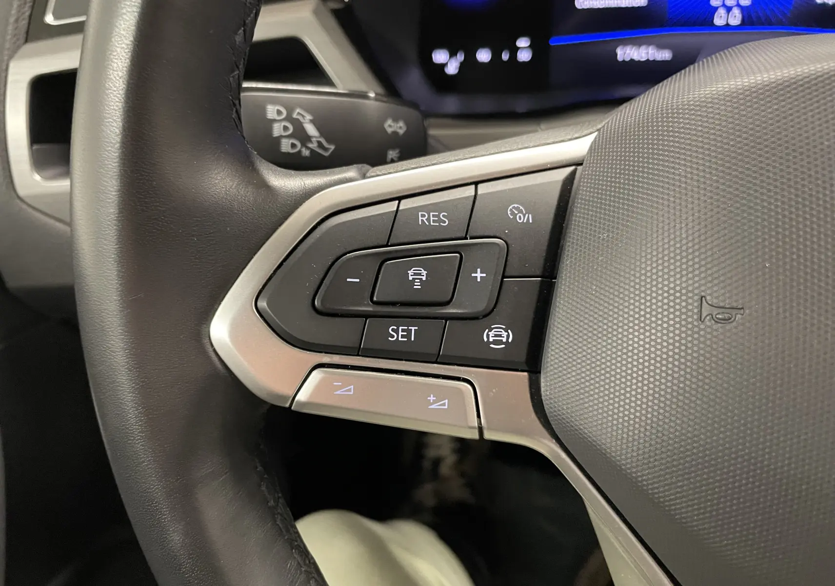 Gros plan sur les commandes de régulateur de vitesse au volant du Volkswagen Touran gris Dauphin 2024.