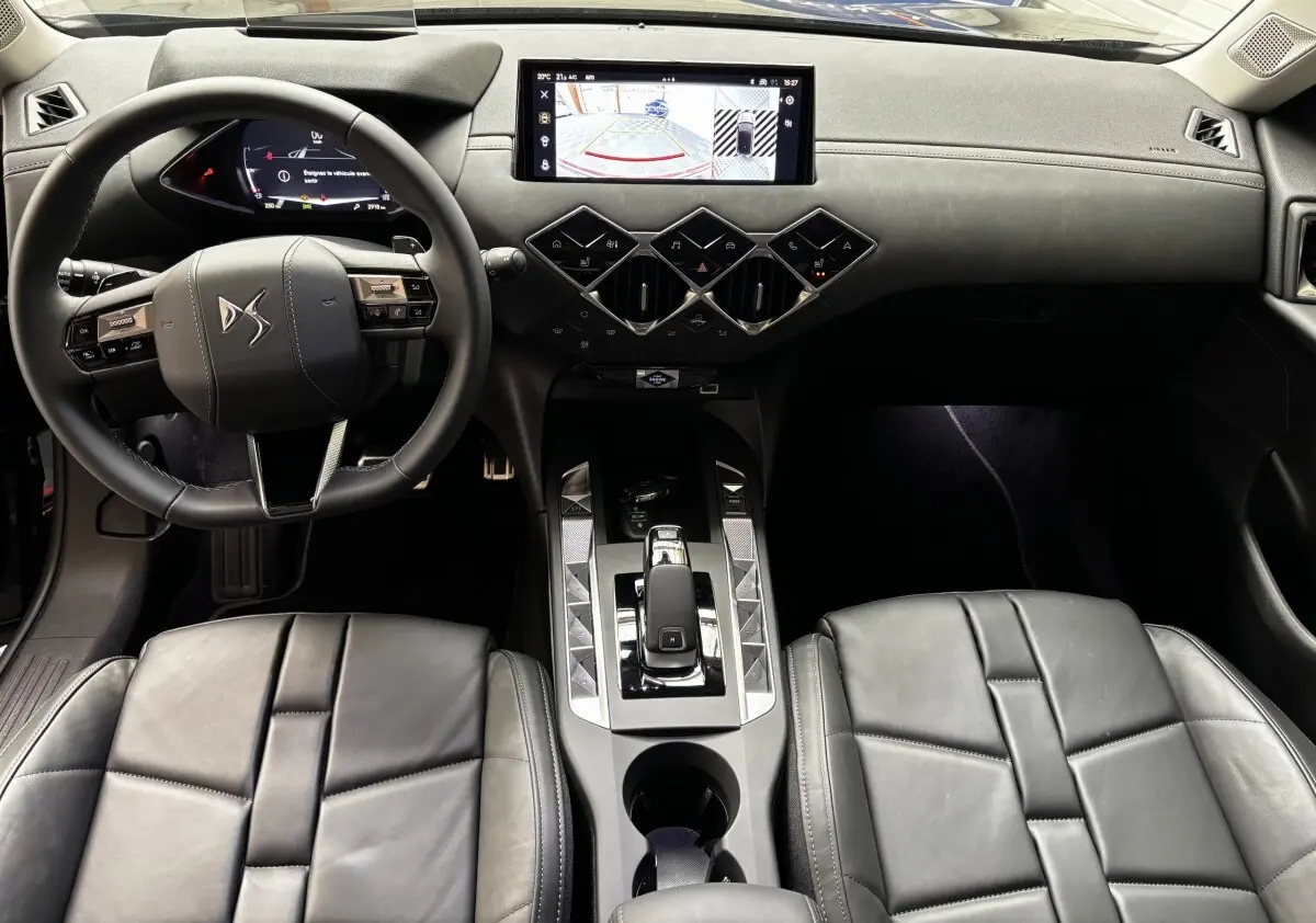 Vue intérieure frontale du tableau de bord et volant cuir noir du DS3 2024 avec écran tactile central et commandes géométriques.