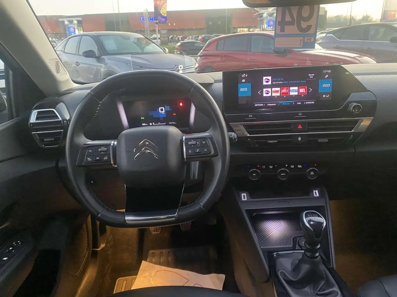 Vue intérieure du poste de conduite de la Citroën C4 blanche 2021, volant multifonction et écran tactile central visible.