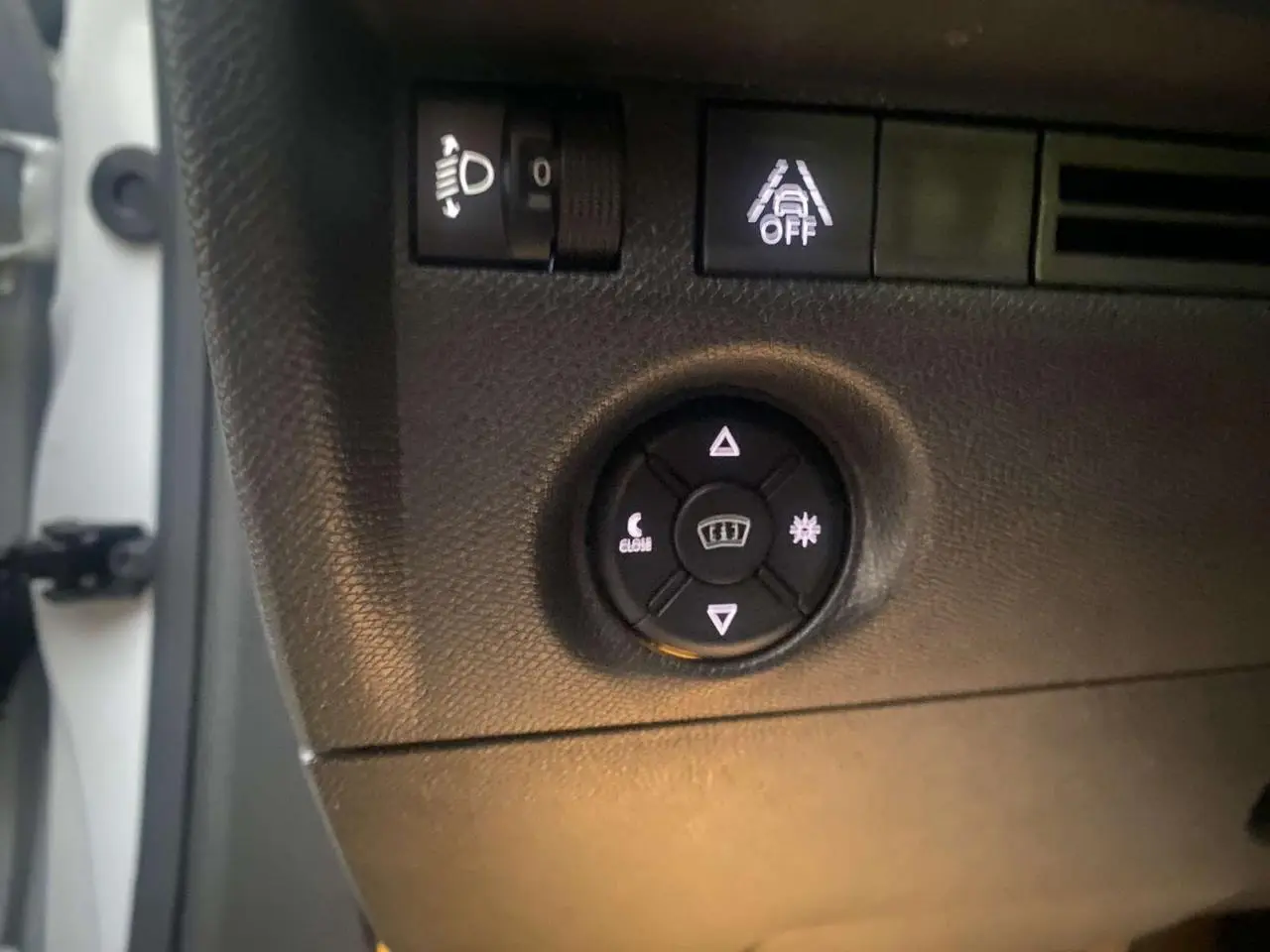 Détail du tableau de bord côté gauche d’une Citroën C4 blanche 2021, montrant les commandes d’éclairage et d’aide à la conduite.