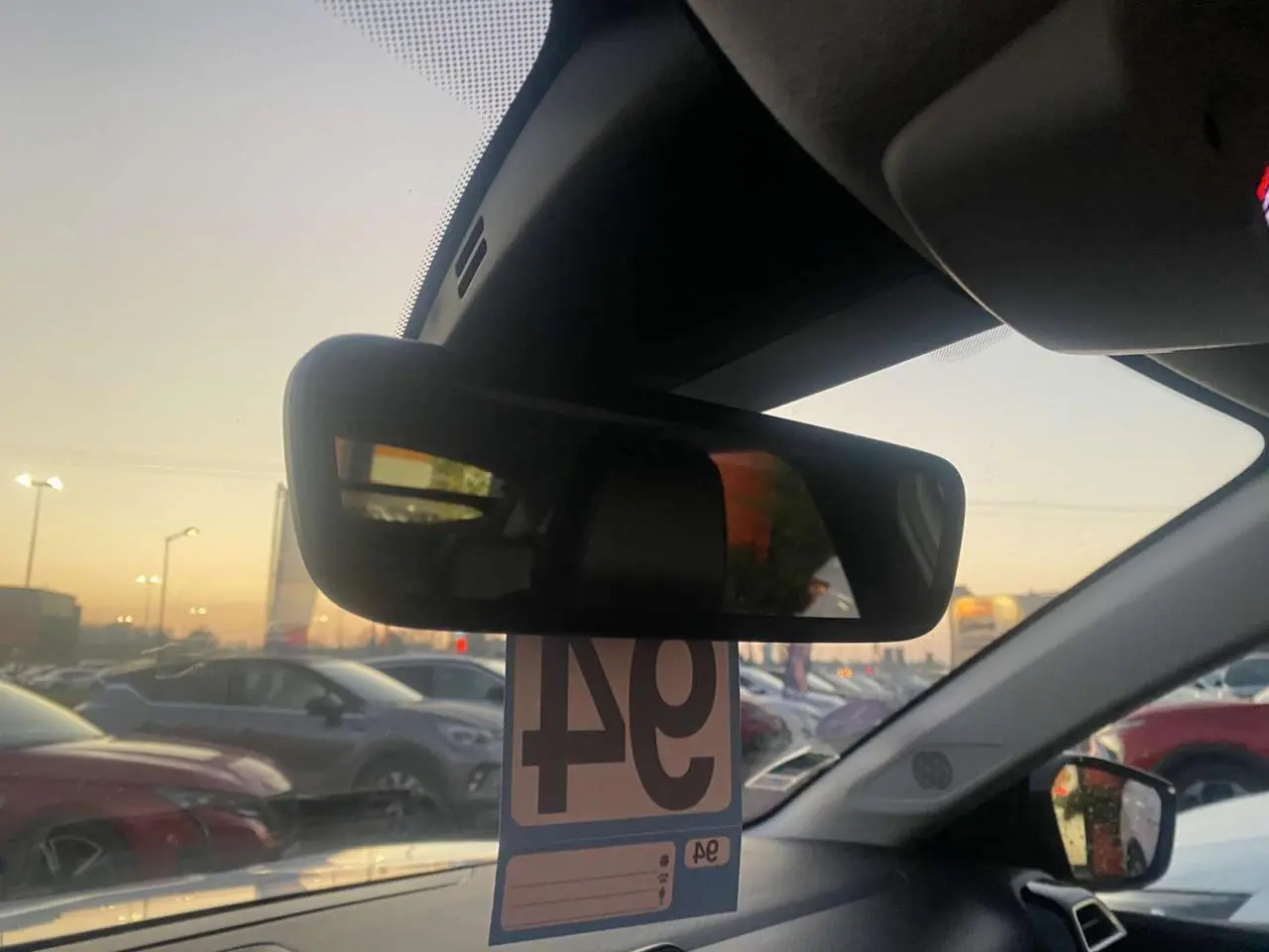 Vue intérieure du rétroviseur central d'une Citroën C4 blanche 2021, avec vue sur un parking au crépuscule.