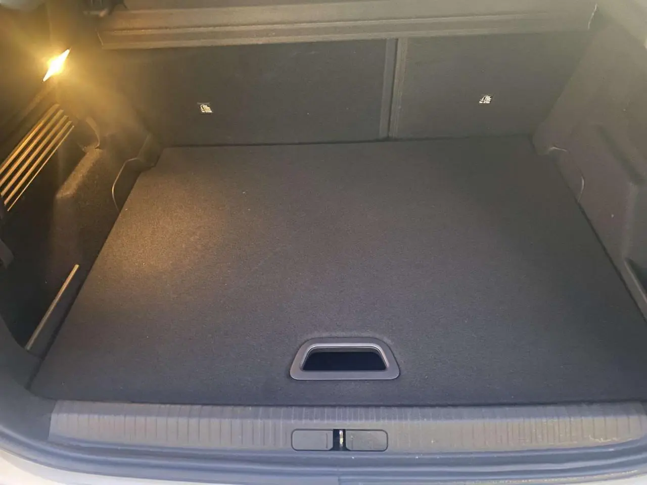 Coffre ouvert de Citroën C4 blanc 2021, vue intérieure montrant le plancher plat et l'éclairage latéral.