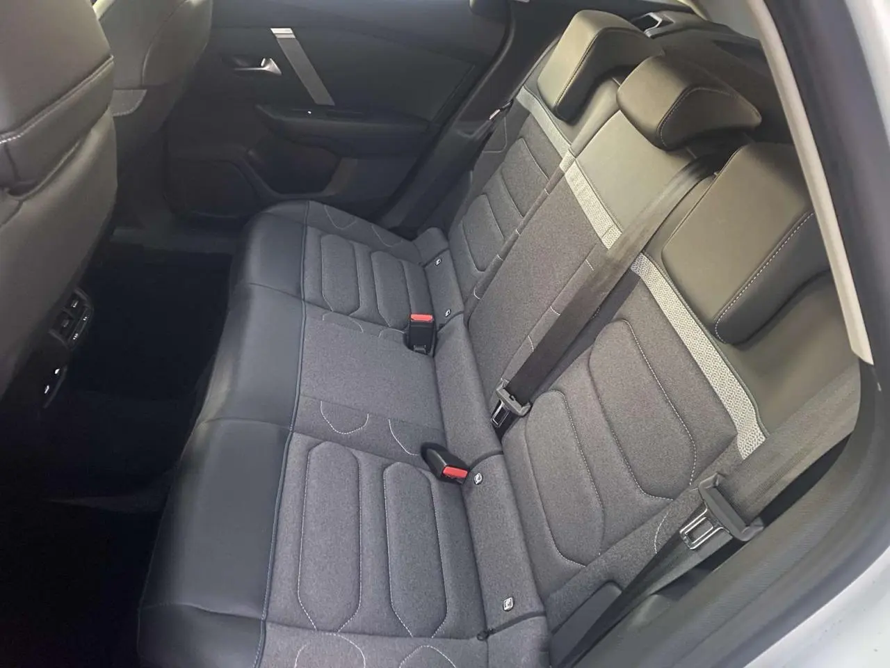 Vue intérieure montrant la banquette arrière grise et noire du Citroën C4 blanc, avec ceintures de sécurité et appuie-têtes.