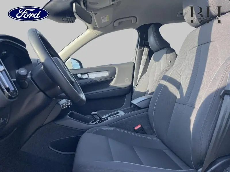 Intérieur avant du Volvo XC40 T5 Recharge gris, vue côté conducteur montrant sièges et volant cuir noir.