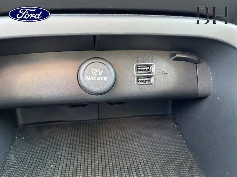Image montrant en gros plan une prise 12V et deux ports USB intégrés dans la console centrale d'un véhicule.