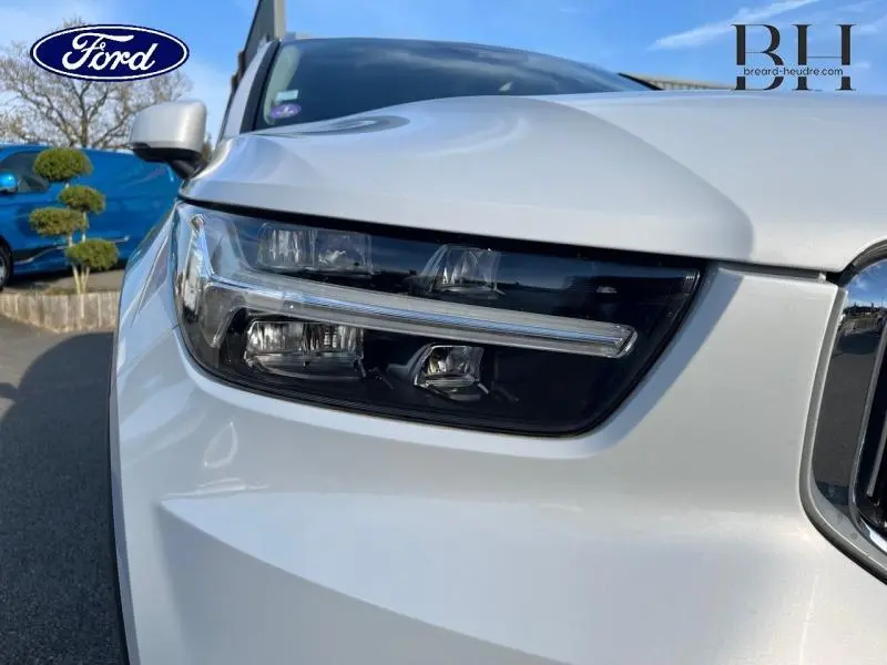 Gros plan sur le phare avant gauche du Volvo XC40 gris Glacier, soulignant la signature lumineuse LED distinctive.