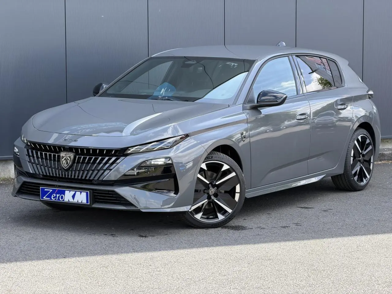 Peugeot 308 NV Hybrid gris Selenium en 3/4 avant droit, avec jantes alliage bi-tons et calandre distinctive.