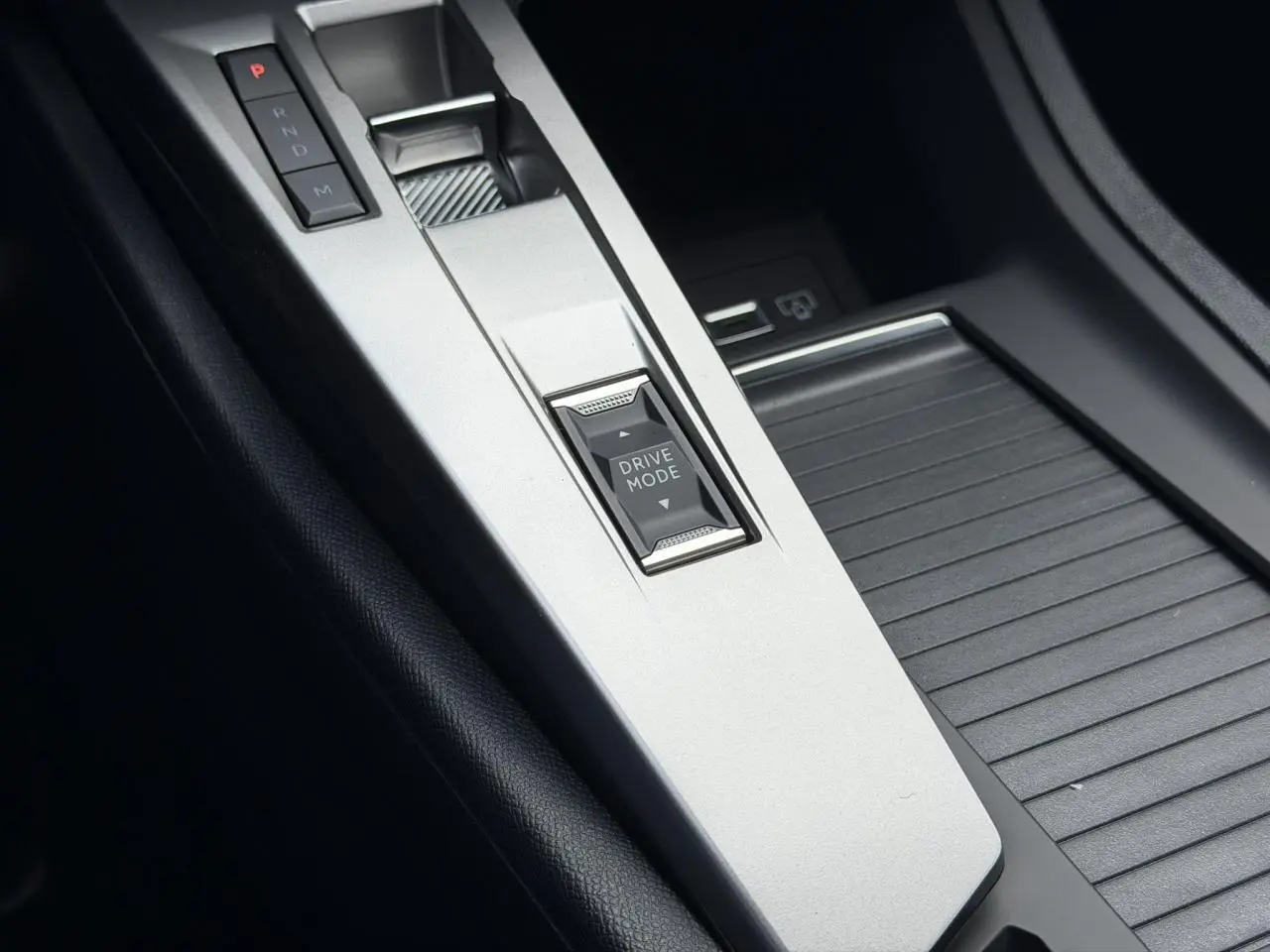 Vue rapprochée de la console centrale argentée avec bouton Drive Mode et levier de vitesses de la Peugeot 308 Hybrid.