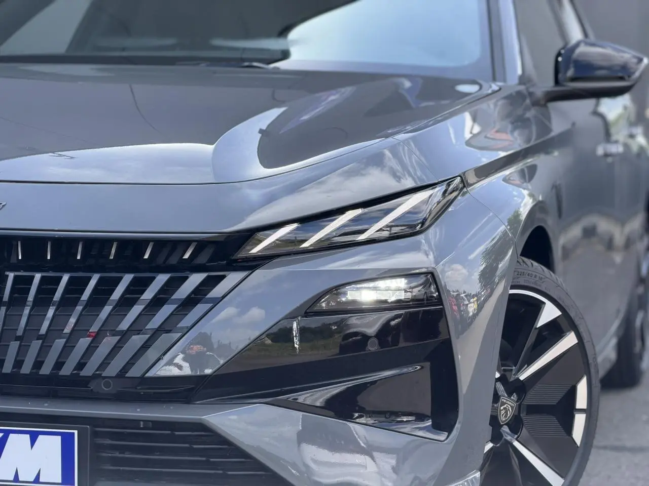 Gros plan 3/4 avant droit du Peugeot 308 NV Hybrid gris Selenium avec phares LED et jantes alliage bi-tons.