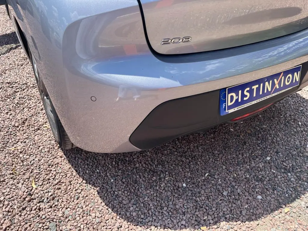 Vue arrière côté gauche du Peugeot 208 gris clair 2023 avec logo 208 et plaque d'immatriculation Distinxion.