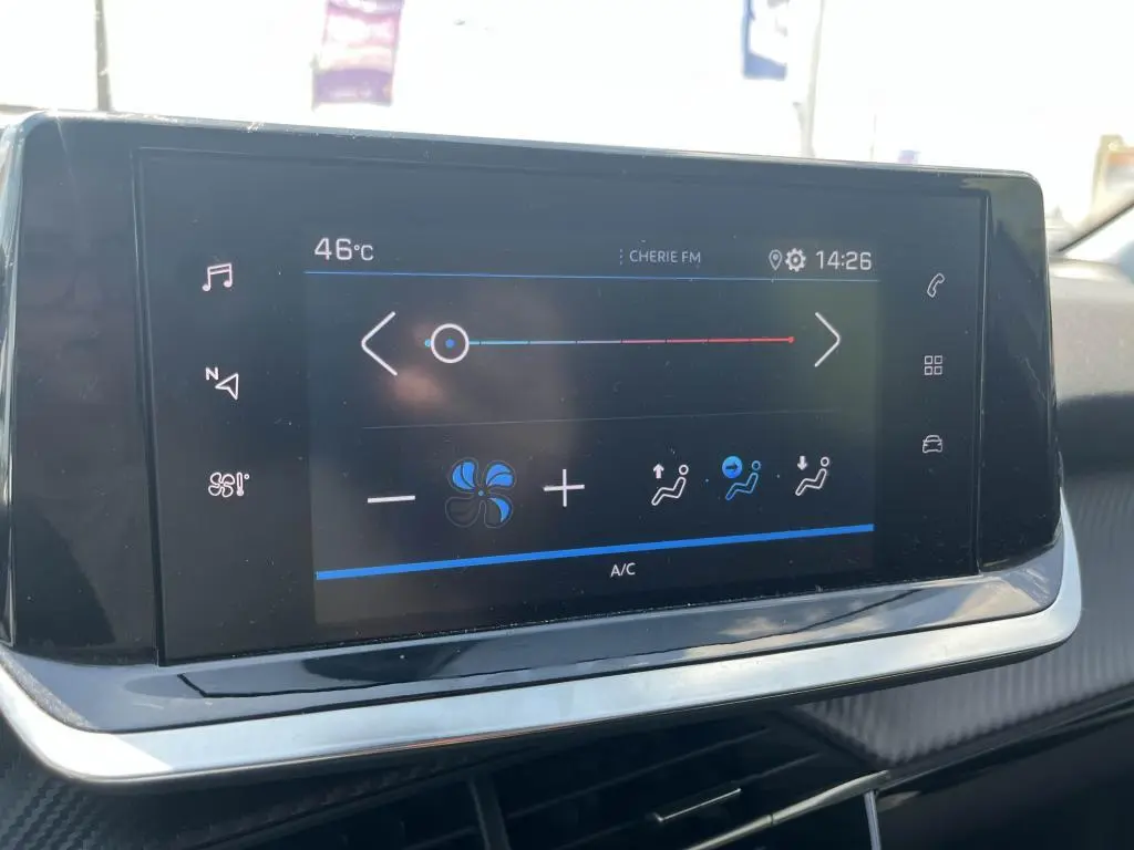 Écran tactile central de la Peugeot 208 2023 en gris clair, affichant les réglages de climatisation et la température extérieure.
