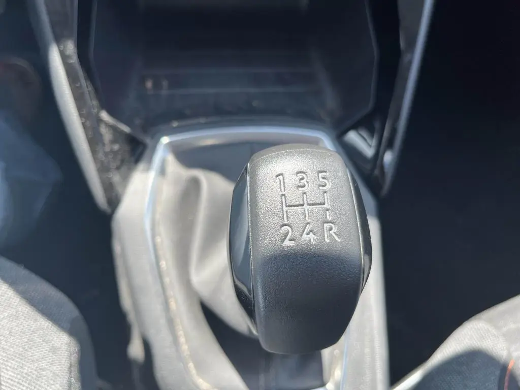 Gros plan sur le levier de vitesses manuel noir de la Peugeot 208 gris clair 2023, montrant les rapports gravés.
