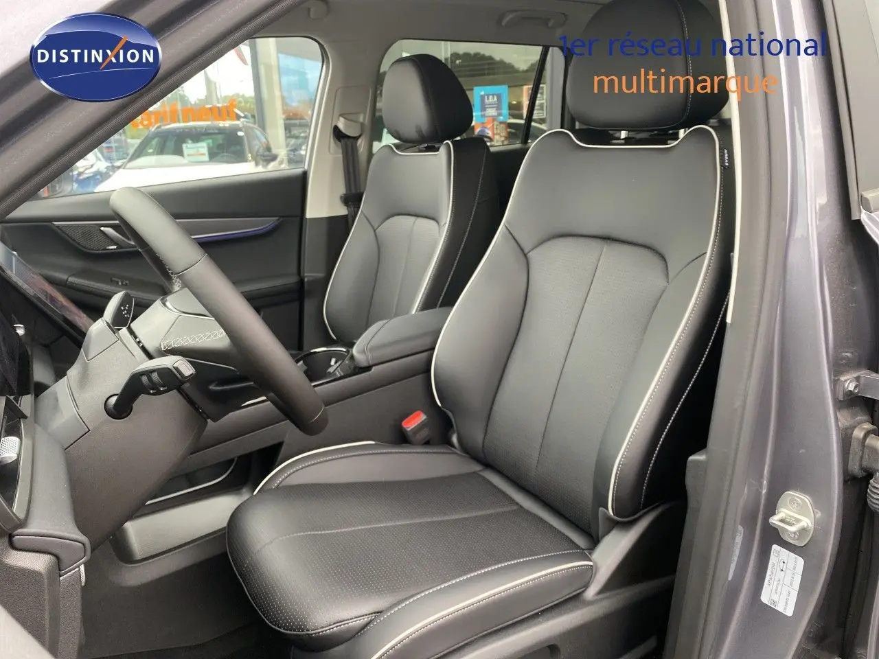 Vue intérieure côté conducteur du JAECOO J5 2026 gris Phantom, sièges cuir noirs avec surpiqûres blanches et volant cuir.