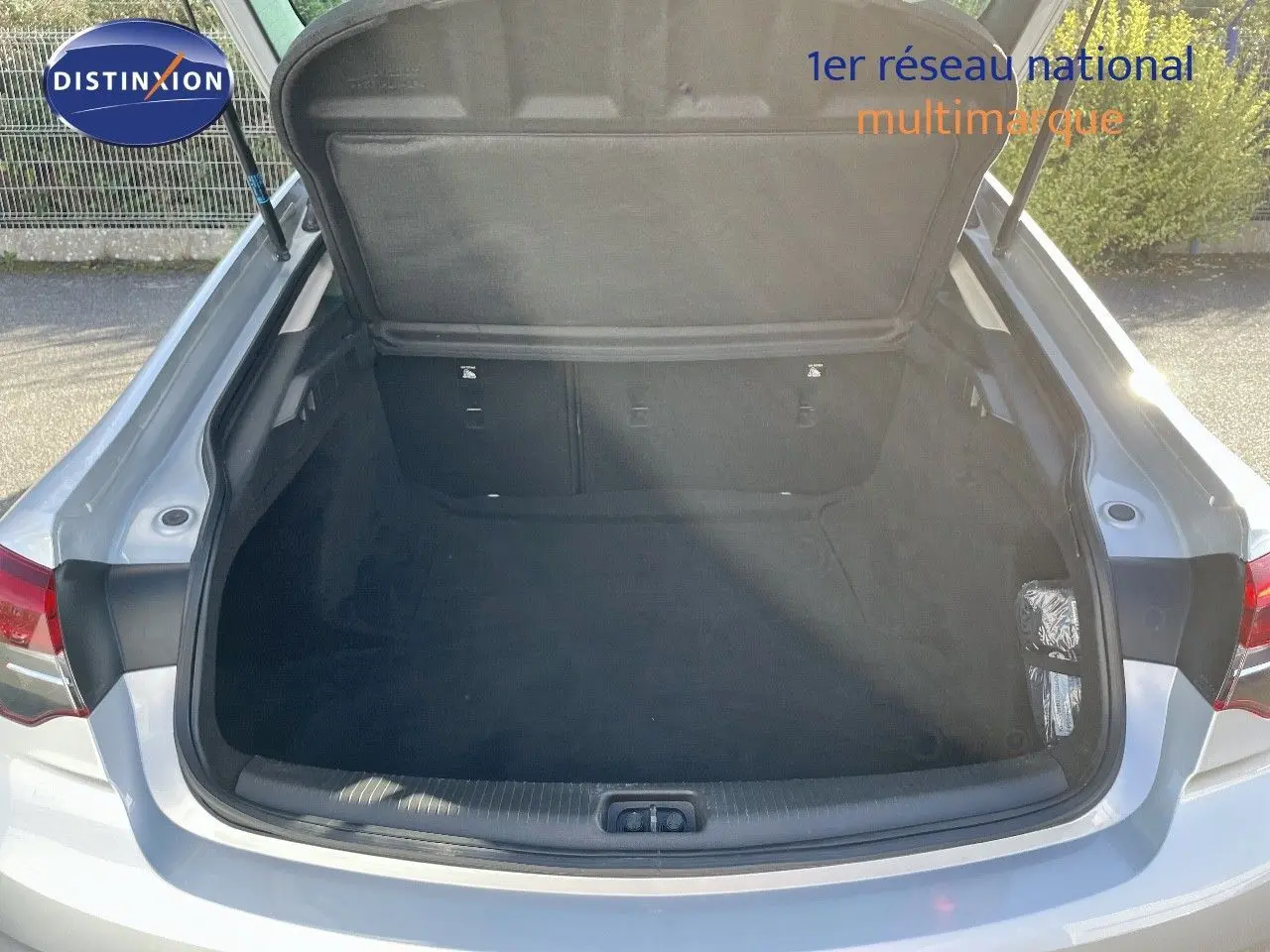 Coffre ouvert vu de l'arrière d'une Opel Insignia gris minéral métal, montrant un espace de chargement vide et propre.