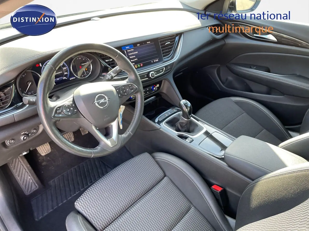 Vue intérieure côté conducteur de l'Opel Insignia 2.0D gris minéral, avec volant cuir, tableau de bord digital et boîte manuelle.