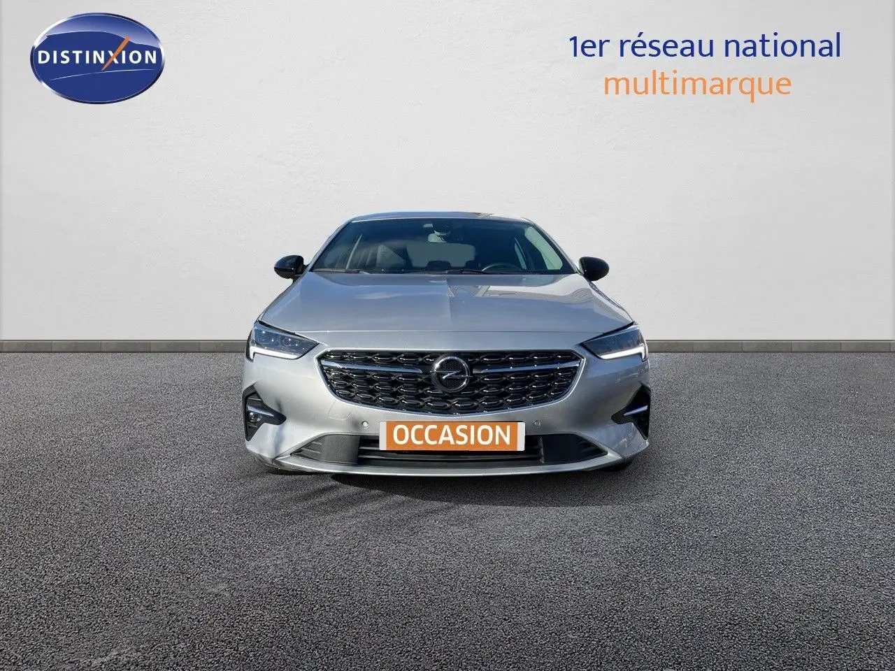 Opel Insignia gris minéral métal vue de face avec calandre noire et phares LED allumés sur fond neutre.