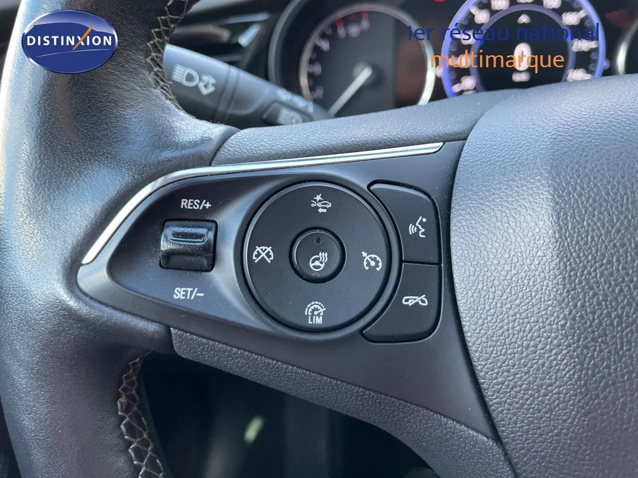 Gros plan sur les commandes au volant de l'Opel Insignia 2.0D 174CH Elegance, volant en cuir noir avec surpiqûres.