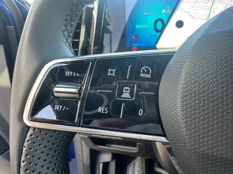 Gros plan sur les commandes du volant du Renault Austral 2025 Bleu Iron, avec boutons de régulateur et mode de conduite visibles.