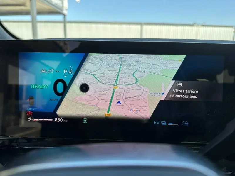 Affichage numérique du tableau de bord du Renault Austral 2025 montrant la navigation GPS et l'état du véhicule en mode hybride.