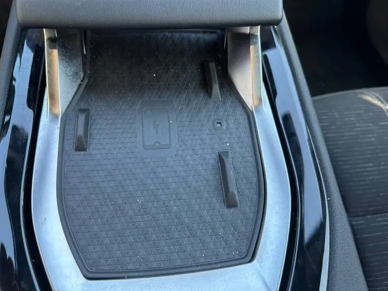 Vue rapprochée de la zone de charge sans fil noire au centre de la console intérieure du Renault Austral Bleu Iron 2025.