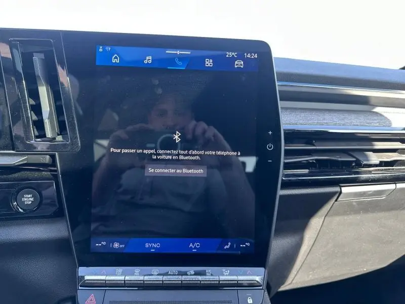 Vue rapprochée de l'écran tactile central du tableau de bord du Renault Austral 2025 Bleu Iron avec commandes climatisation visibles.