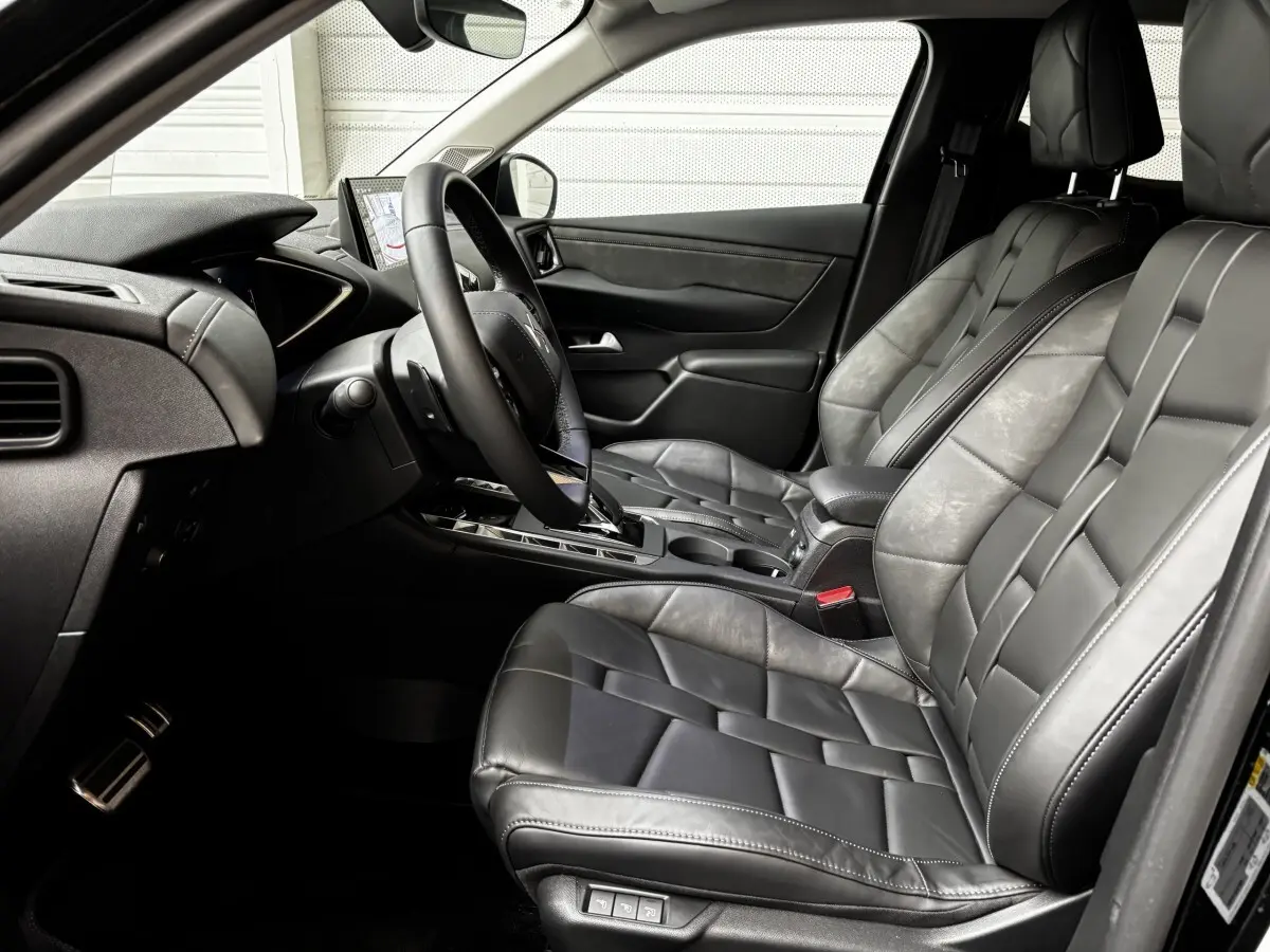 Vue intérieure côté conducteur de la DS3 2024, sièges cuir noirs et tableau de bord avec écran tactile visible.
