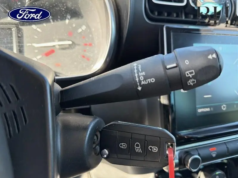 Gros plan sur la commande d'essuie-glace et la clé de contact dans l'habitacle d'une Citroën C3 Aircross gris acier.