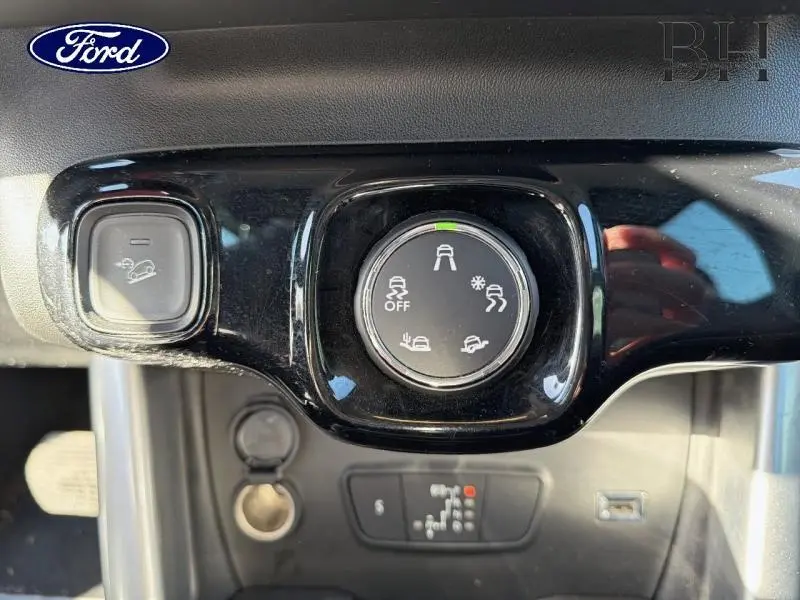 Gros plan sur le sélecteur de modes de conduite et bouton d'aide à la descente dans un intérieur noir brillant.